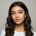 Woman with long, wavy hair wearing a white shirt against a neutral background